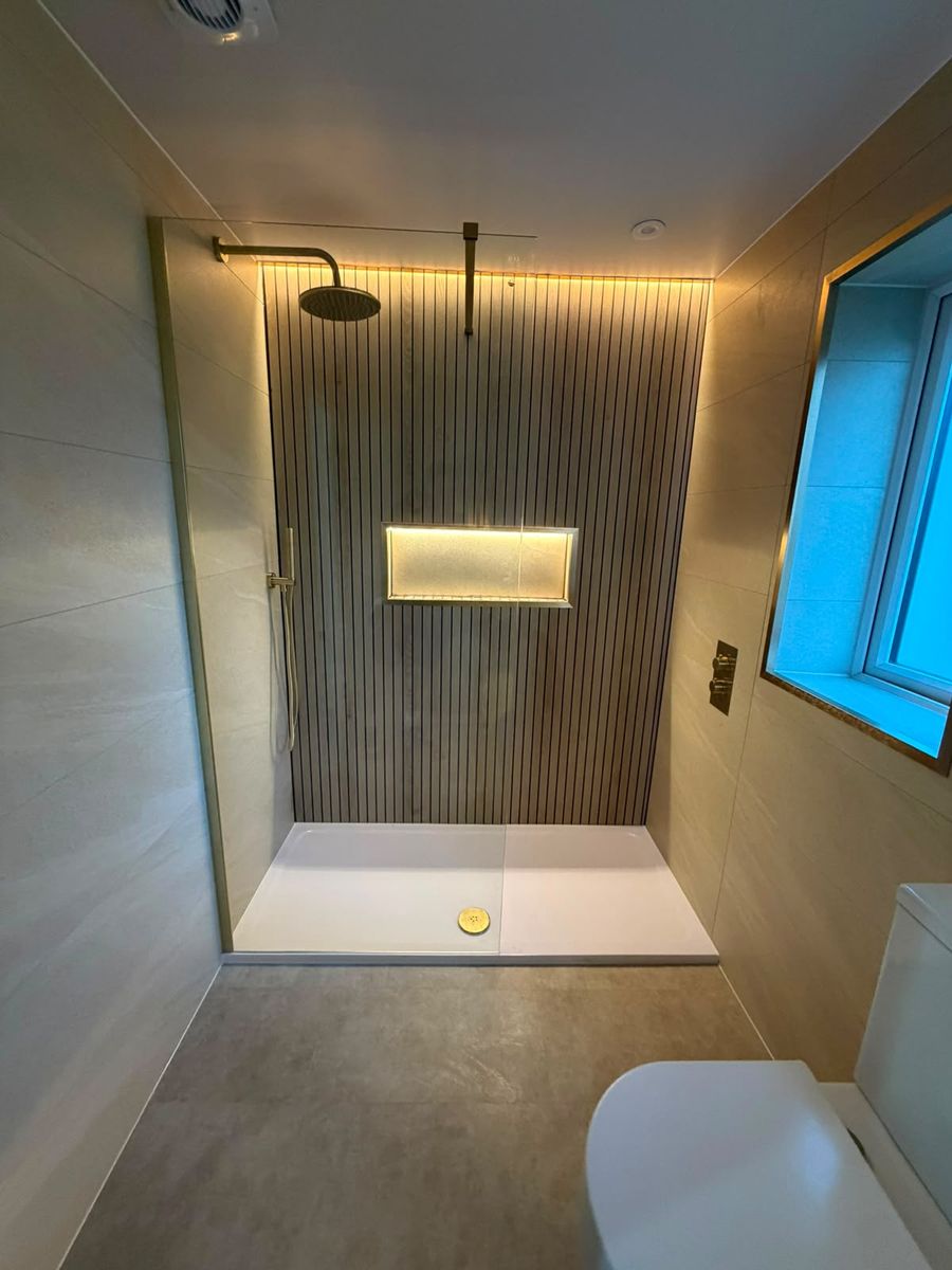 Walk-in shower with panelled feature wall and lit niche