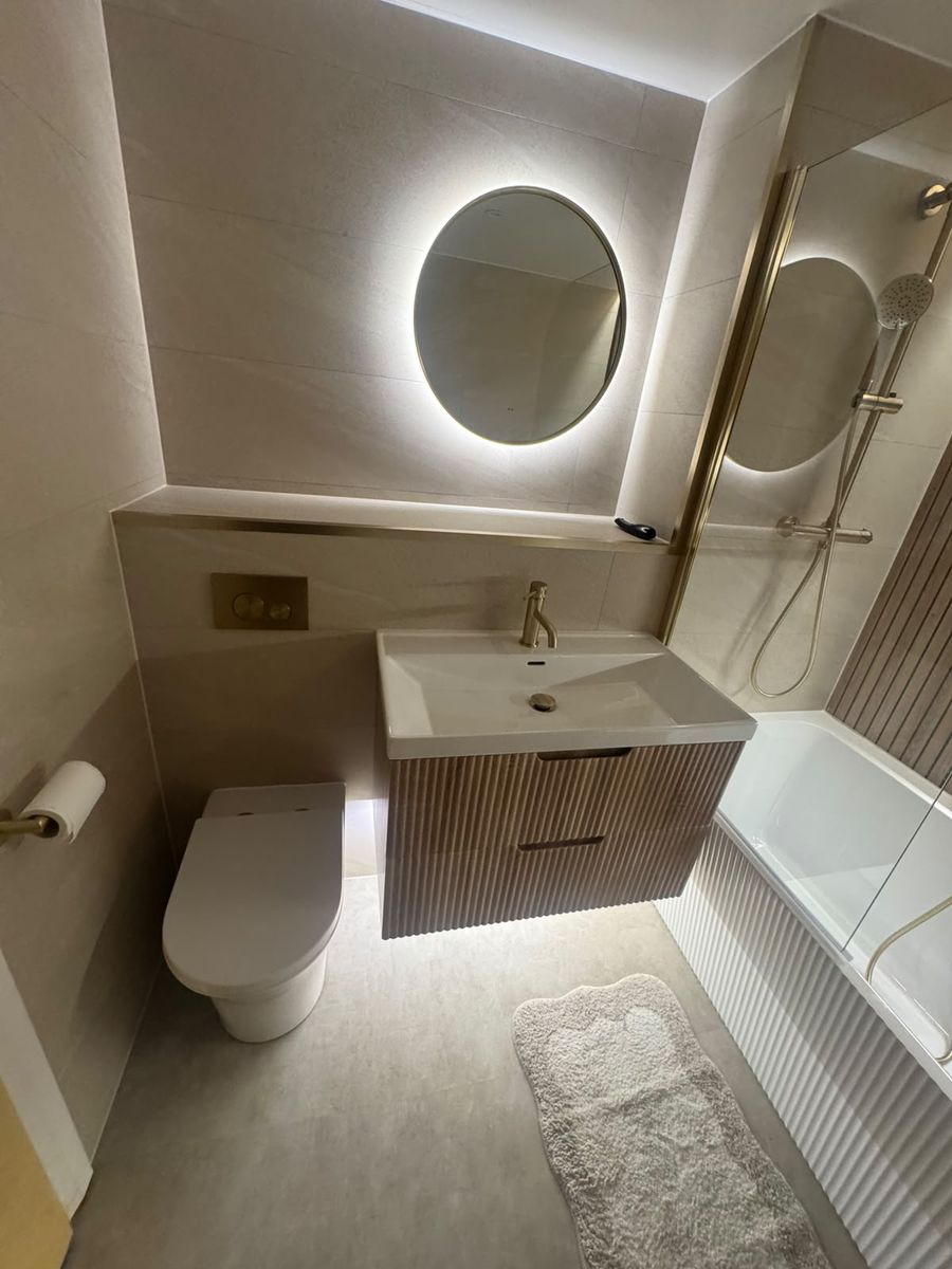 Backlit round mirror and floating vanity with brass tap